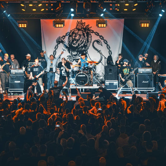 A large custom backdrop designed for a band, featuring a graphic print, displayed at a concert with the band performing on stage in front of it.